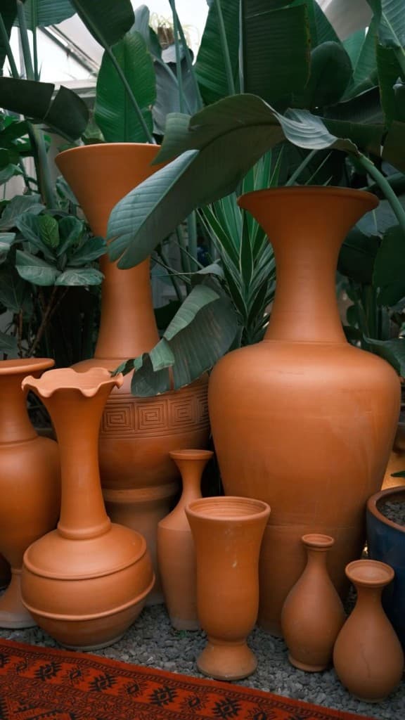 Tall terracotta vases set among tropical leaves